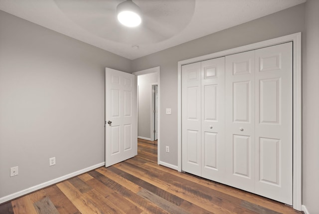 unfurnished bedroom with ceiling fan, dark hardwood / wood-style flooring, and a closet