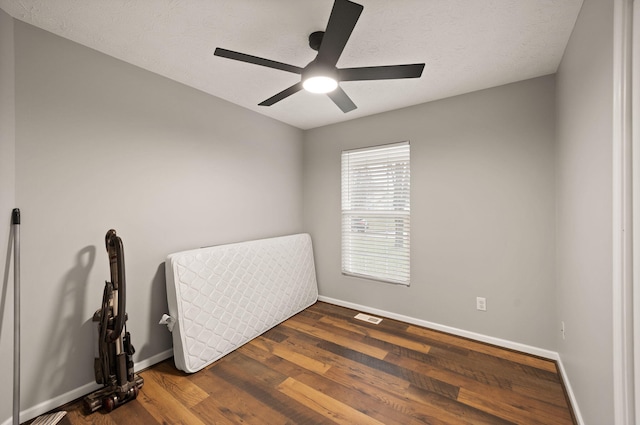 bedroom featuring ceiling fan, dark hardwood / wood-style flooring, and a textured ceiling