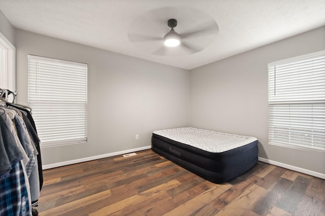 bedroom with a textured ceiling, ceiling fan, and dark wood-type flooring