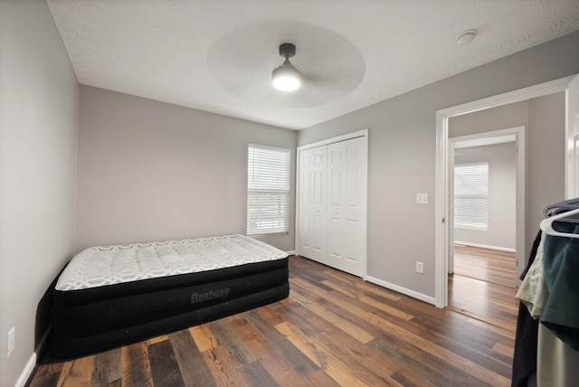 bedroom featuring ceiling fan, a closet, dark wood-type flooring, and a textured ceiling