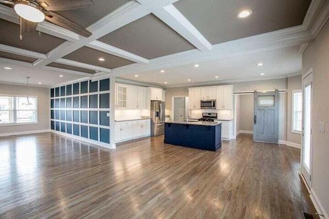 kitchen featuring a center island with sink, hardwood / wood-style flooring, a barn door, white cabinetry, and stainless steel appliances