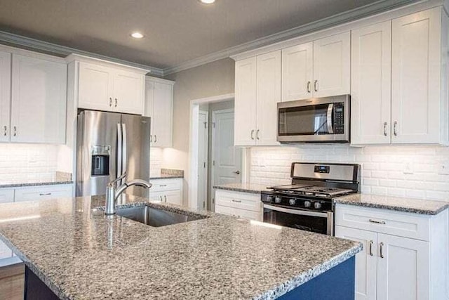 kitchen with white cabinets, a kitchen island with sink, sink, and appliances with stainless steel finishes