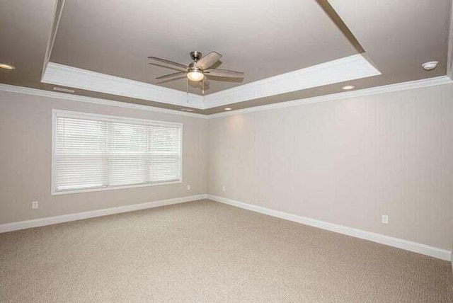 unfurnished room with a raised ceiling, crown molding, carpet flooring, and ceiling fan