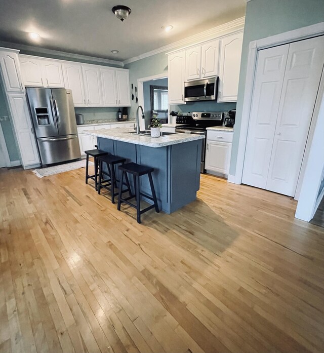 kitchen featuring a center island with sink, a kitchen bar, white cabinetry, and stainless steel appliances