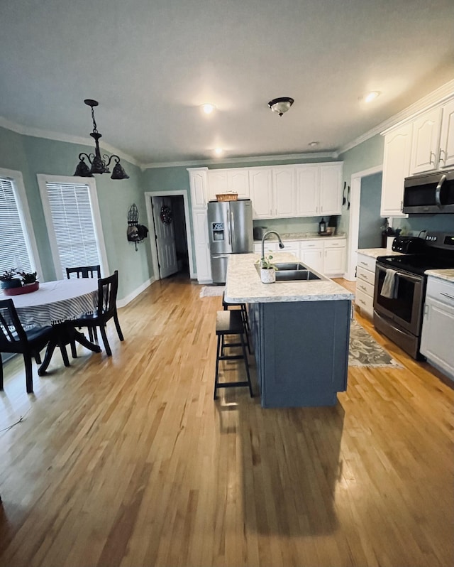 kitchen with sink, light hardwood / wood-style flooring, an island with sink, white cabinetry, and stainless steel appliances