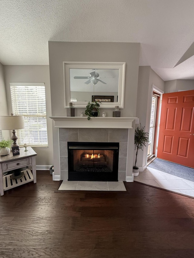 room details featuring hardwood / wood-style floors, ceiling fan, a textured ceiling, and a tiled fireplace