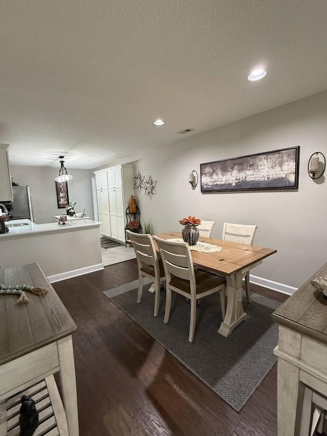 dining area with dark hardwood / wood-style floors and a textured ceiling