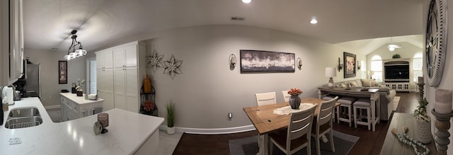 dining space with dark hardwood / wood-style flooring, lofted ceiling, and sink