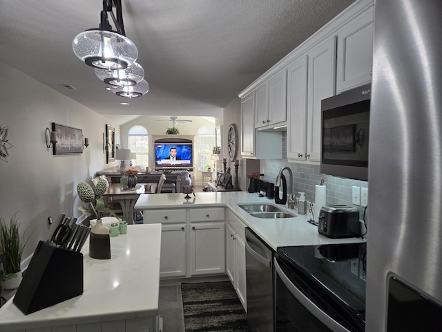 kitchen with pendant lighting, white cabinets, sink, kitchen peninsula, and stainless steel appliances