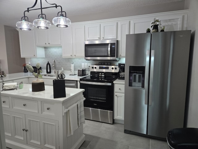 kitchen with backsplash, stainless steel appliances, light tile patterned floors, white cabinets, and hanging light fixtures