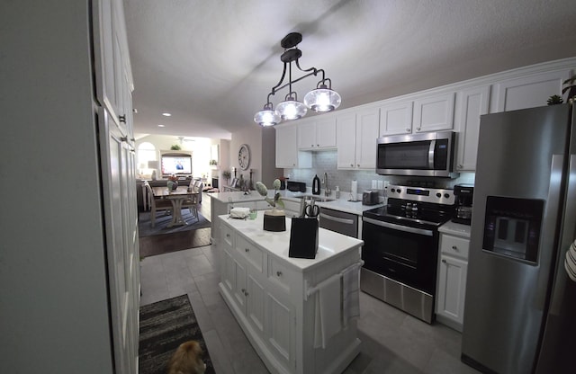 kitchen with white cabinetry, a center island, pendant lighting, decorative backsplash, and appliances with stainless steel finishes