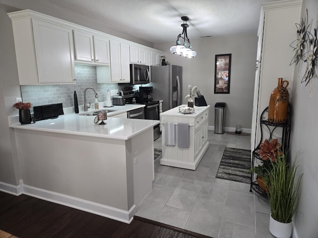 kitchen featuring white cabinetry, sink, pendant lighting, a kitchen island, and appliances with stainless steel finishes