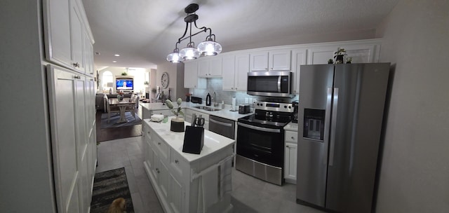 kitchen featuring appliances with stainless steel finishes, a center island, decorative light fixtures, and white cabinetry