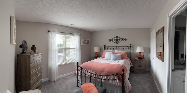 bedroom featuring vaulted ceiling, a textured ceiling, and dark colored carpet