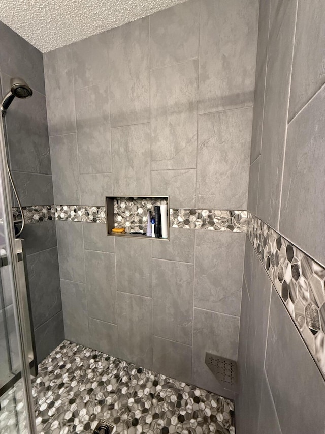 bathroom with a textured ceiling and tiled shower