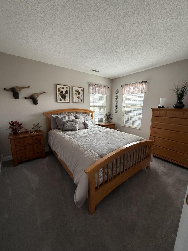 bedroom featuring dark colored carpet and a textured ceiling