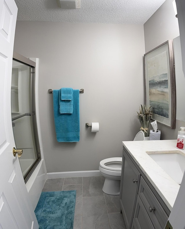 full bathroom featuring vanity, shower / bath combination with glass door, tile patterned floors, toilet, and a textured ceiling