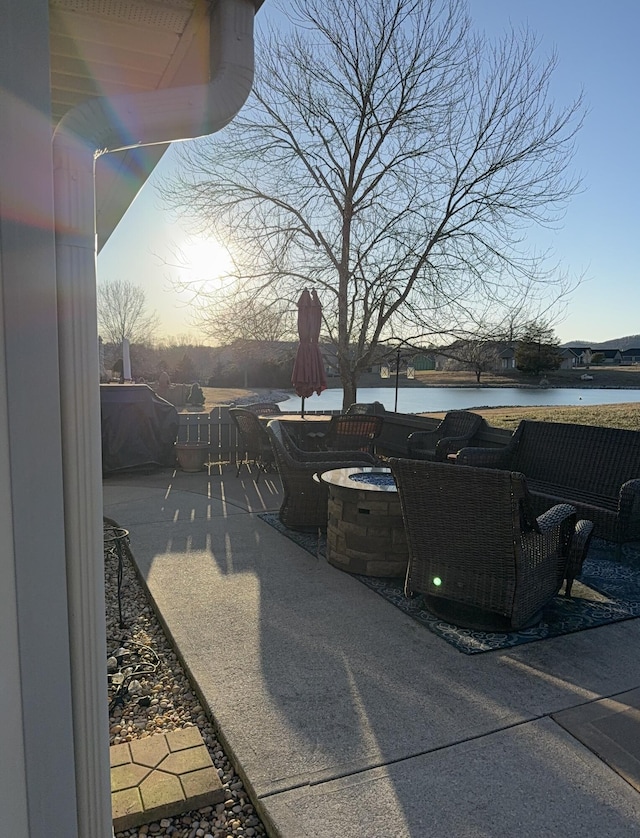 patio terrace at dusk featuring a water view and a fire pit