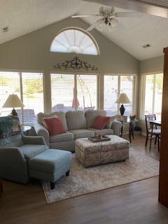 living room featuring wood-type flooring, ceiling fan, and vaulted ceiling