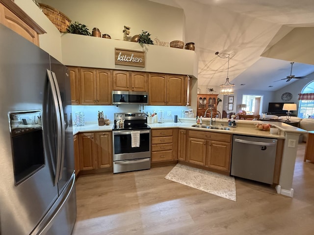 kitchen with sink, light hardwood / wood-style flooring, appliances with stainless steel finishes, kitchen peninsula, and pendant lighting