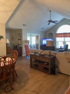 living room with ceiling fan, lofted ceiling, and hardwood / wood-style floors