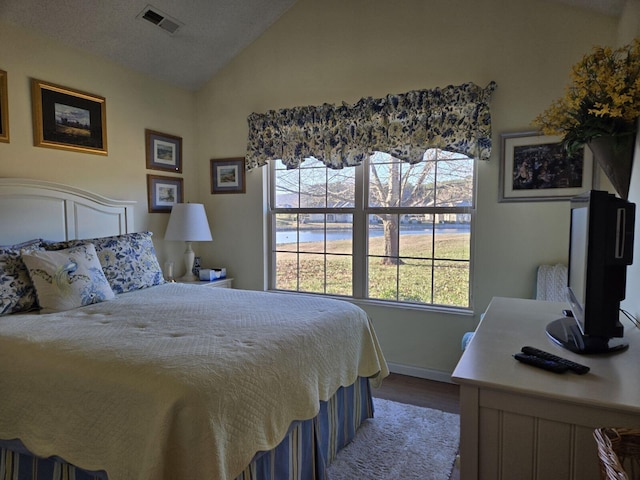 bedroom with lofted ceiling, hardwood / wood-style flooring, multiple windows, and a textured ceiling