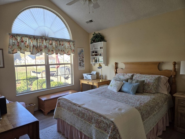 bedroom with lofted ceiling, hardwood / wood-style flooring, a textured ceiling, and ceiling fan