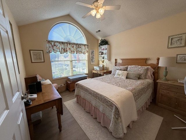 bedroom with a textured ceiling, vaulted ceiling, light hardwood / wood-style floors, and ceiling fan