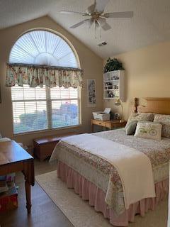 bedroom with ceiling fan, wood-type flooring, and vaulted ceiling