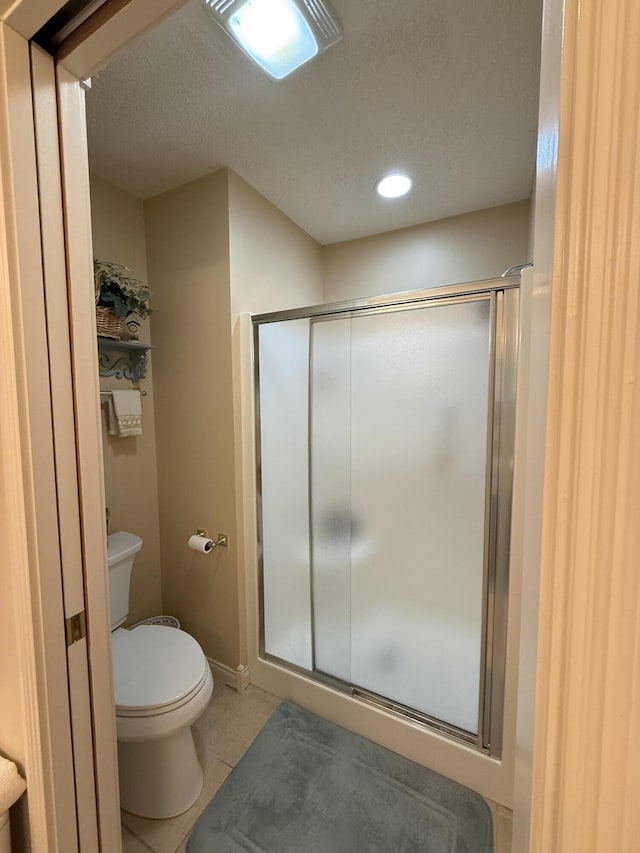 bathroom featuring tile patterned flooring, toilet, a textured ceiling, and walk in shower