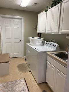 laundry room with sink, cabinets, washing machine and clothes dryer, and light tile patterned flooring