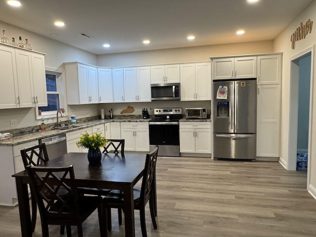 kitchen with sink, white cabinets, light hardwood / wood-style floors, and appliances with stainless steel finishes