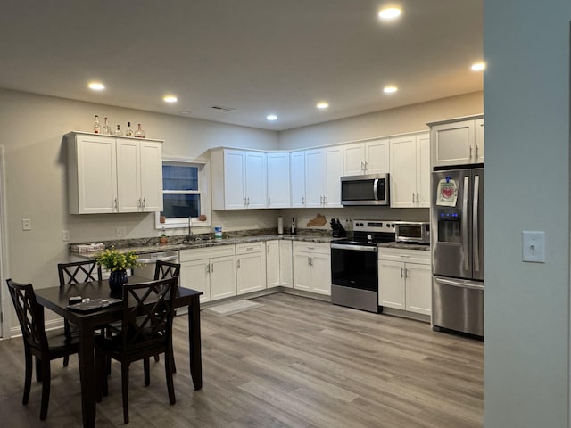 kitchen with white cabinets, stainless steel appliances, light hardwood / wood-style flooring, and sink