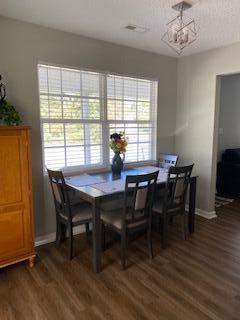 dining space featuring dark wood-type flooring and a notable chandelier