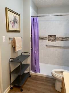 bathroom with a shower with curtain, a textured ceiling, toilet, vanity, and hardwood / wood-style flooring