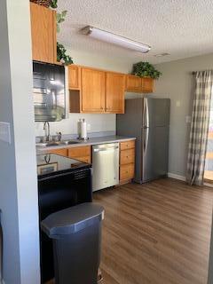 kitchen with a textured ceiling, stainless steel appliances, dark wood-type flooring, and sink