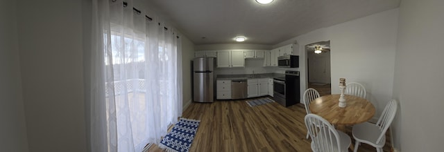 kitchen featuring appliances with stainless steel finishes, dark hardwood / wood-style flooring, white cabinetry, and sink