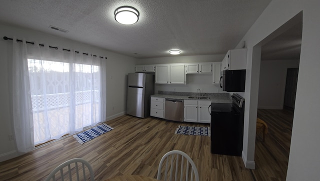 kitchen featuring white cabinets, sink, a textured ceiling, dark hardwood / wood-style flooring, and stainless steel appliances