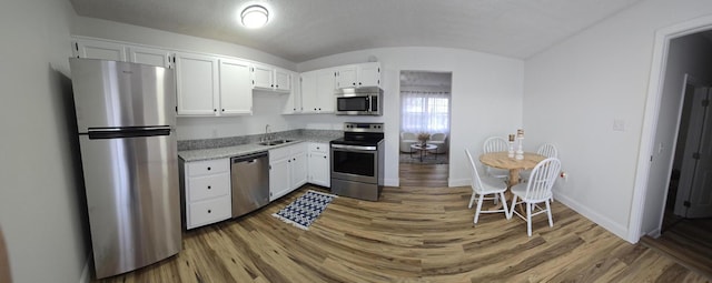 kitchen with white cabinetry, stainless steel appliances, and wood-type flooring