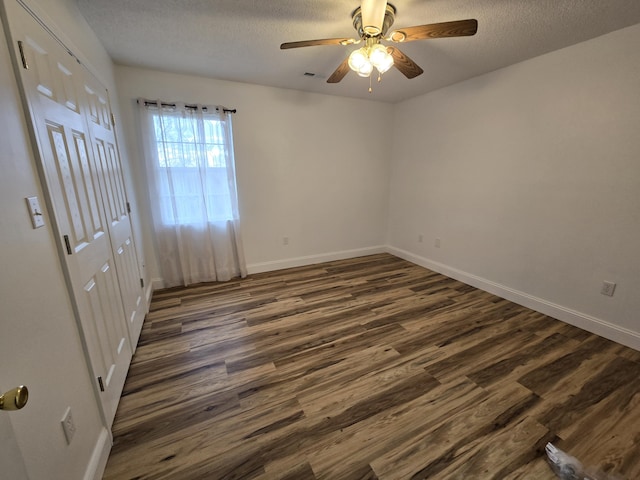 empty room featuring dark hardwood / wood-style floors, ceiling fan, and a textured ceiling