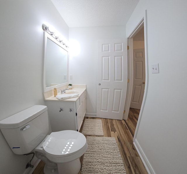 bathroom with vanity, wood-type flooring, a textured ceiling, and toilet