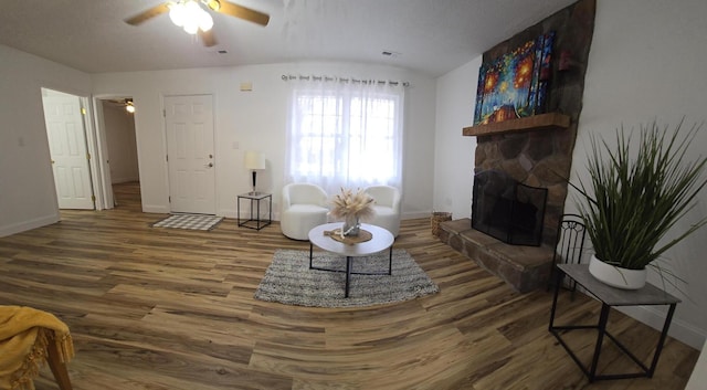 living room featuring a stone fireplace, ceiling fan, and hardwood / wood-style floors