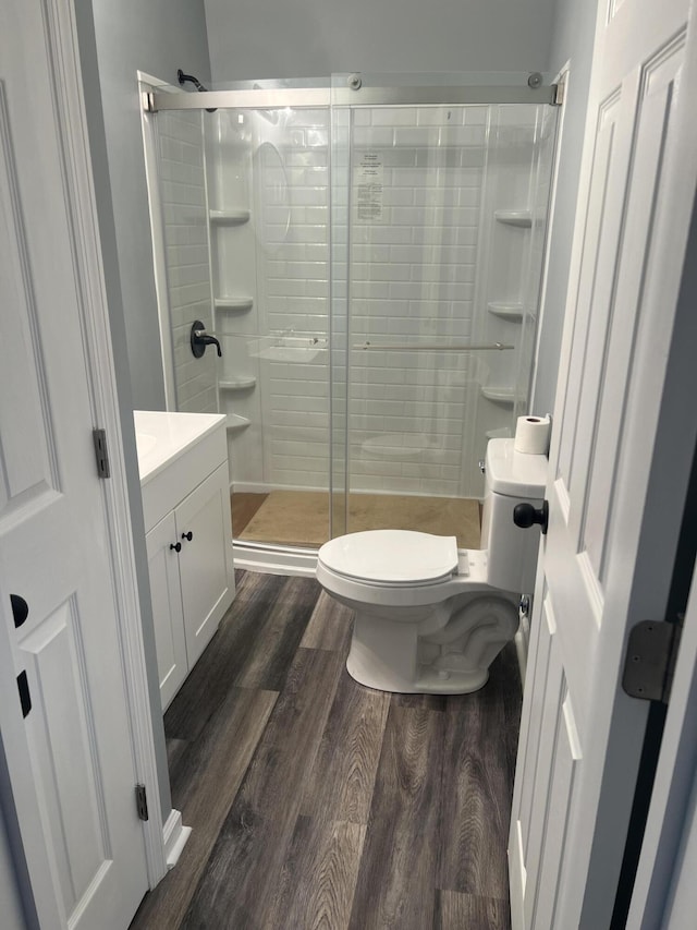 bathroom featuring vanity, wood-type flooring, an enclosed shower, and toilet