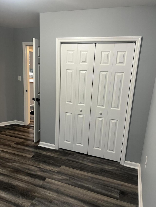 unfurnished bedroom with dark wood-type flooring and a closet