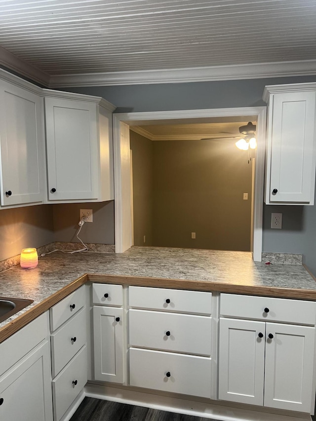 kitchen with dark hardwood / wood-style flooring, white cabinetry, and crown molding