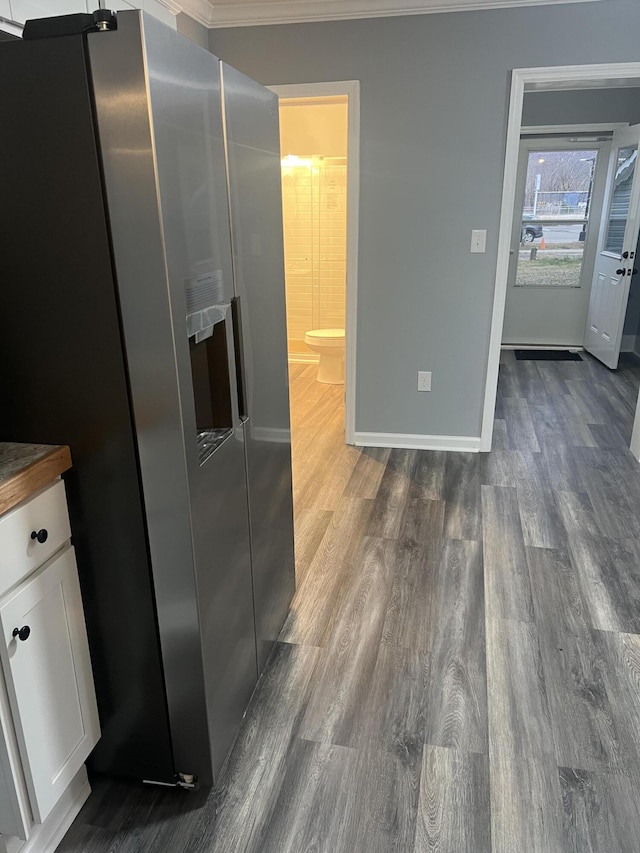 kitchen with white cabinetry, dark hardwood / wood-style flooring, stainless steel refrigerator with ice dispenser, butcher block countertops, and crown molding