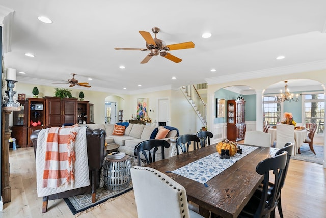 dining space with stairs, arched walkways, and light wood-type flooring