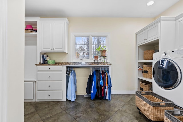 laundry room featuring baseboards, washer / clothes dryer, and cabinet space