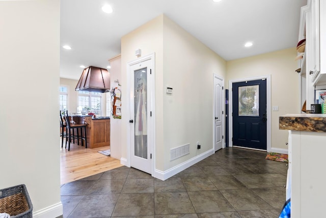 foyer entrance featuring visible vents, recessed lighting, baseboards, and dark tile patterned flooring