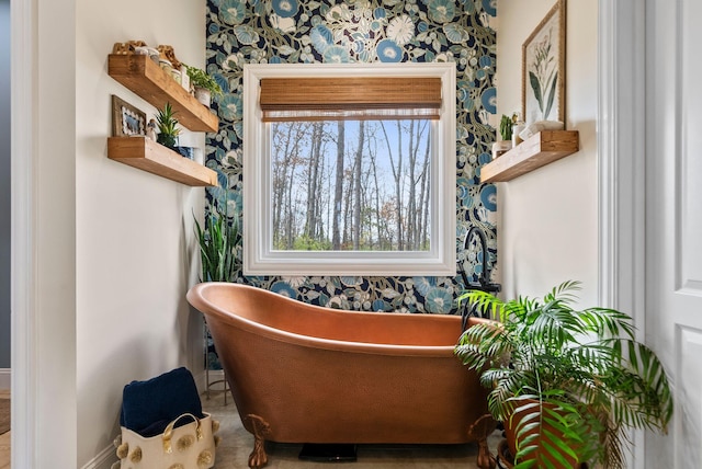 interior space with wallpapered walls, baseboards, and a freestanding tub